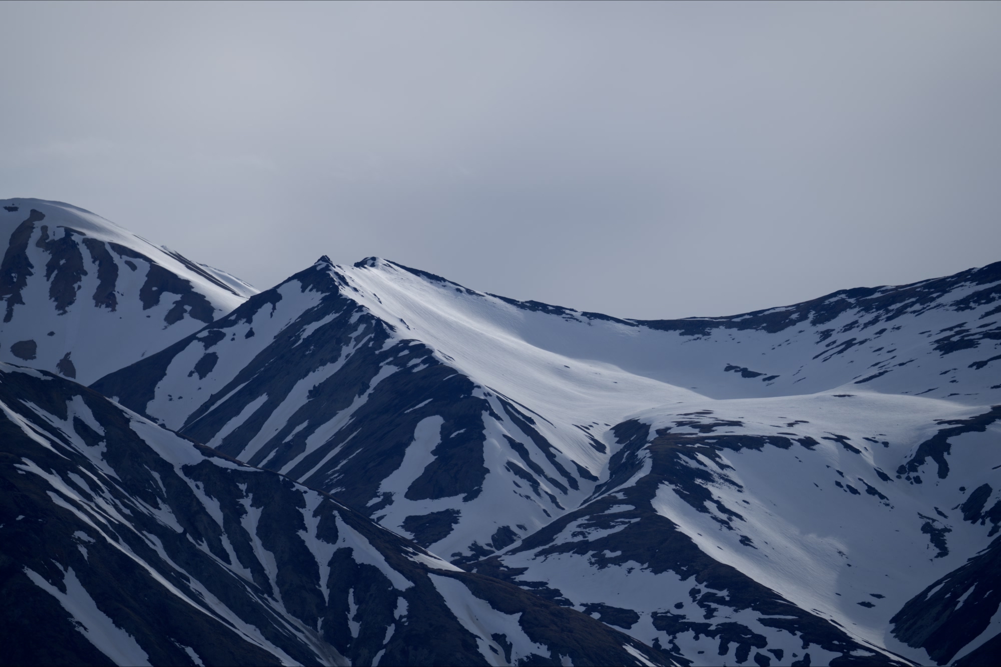 Snowy mountain hills melting in the long June days of the Yukon
